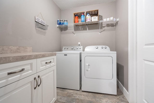 washroom featuring a textured ceiling, washer and clothes dryer, and cabinet space