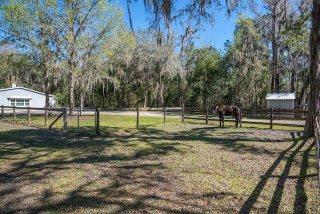 view of yard featuring an outbuilding, a gate, a rural view, and fence