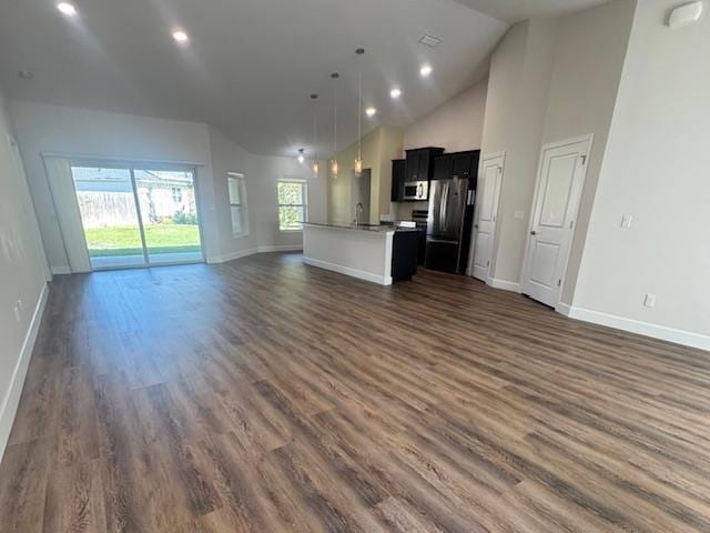 kitchen featuring a center island with sink, appliances with stainless steel finishes, dark hardwood / wood-style flooring, hanging light fixtures, and high vaulted ceiling