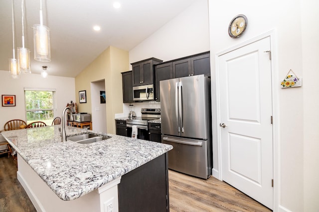 kitchen featuring hanging light fixtures, appliances with stainless steel finishes, sink, and a kitchen island with sink