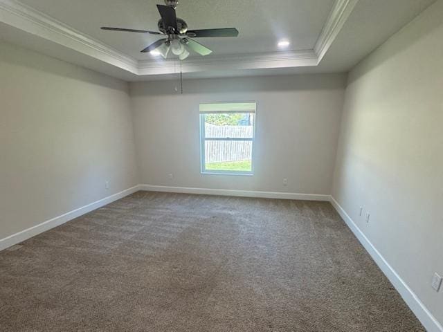 empty room with a tray ceiling, ornamental molding, carpet floors, and ceiling fan