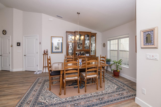 dining area featuring vaulted ceiling, an inviting chandelier, and hardwood / wood-style floors