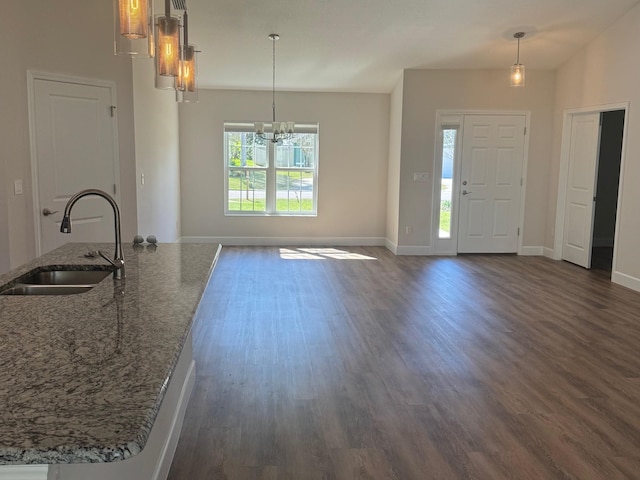 kitchen with sink, dark stone countertops, dark hardwood / wood-style floors, and decorative light fixtures