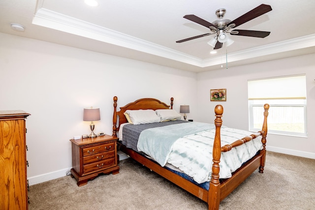 carpeted bedroom with a tray ceiling, ornamental molding, and ceiling fan