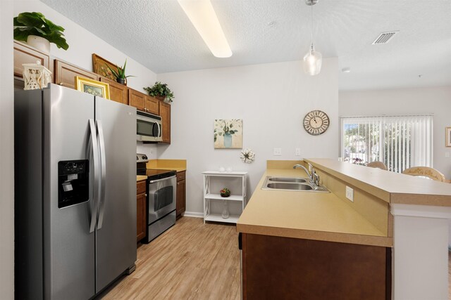 2251 Golden Lake Loop, Saint Augustine, FL 32084 - kitchen featuring appliances with stainless steel finishes, a peninsula, light wood-style floors, light countertops, and a textured ceiling