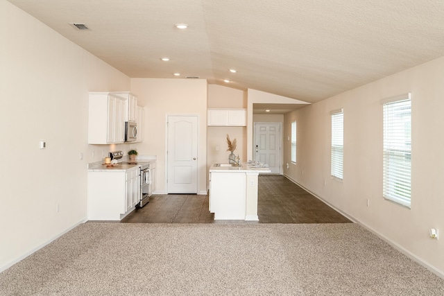 2730 Oak Stream Dr, Green Cove Springs, FL 32043 - kitchen with appliances with stainless steel finishes, lofted ceiling, dark colored carpet, a kitchen island with sink, and white cabinetry
