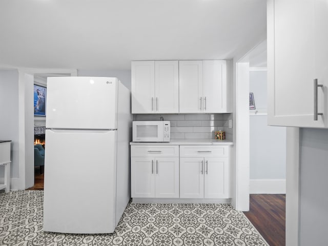 kitchen with tasteful backsplash, white cabinets, and white appliances