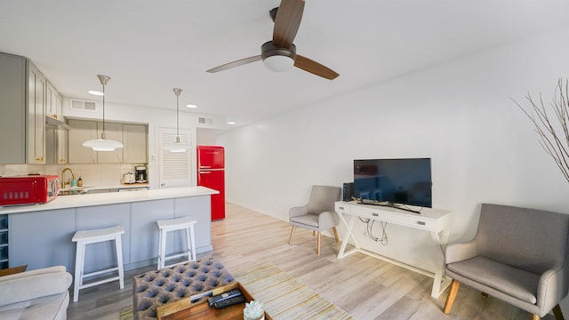 living room with sink, ceiling fan, and light wood-type flooring