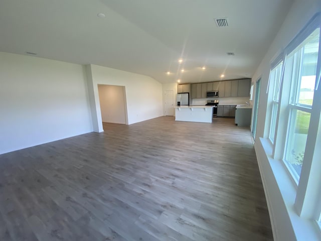 unfurnished living room with lofted ceiling, a healthy amount of sunlight, and wood-type flooring