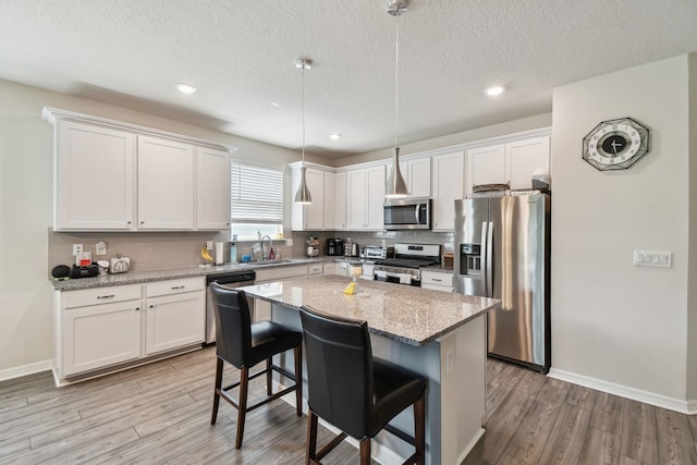 182 Myrtle Oak Ct, Saint Augustine, FL 32092 - kitchen featuring appliances with stainless steel finishes, a sink, light wood-type flooring, white cabinetry, and a textured ceiling
