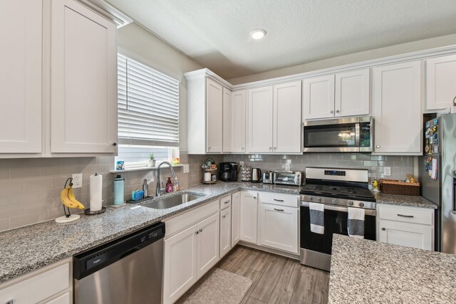 182 Myrtle Oak Ct, Saint Augustine, FL 32092 - kitchen featuring stainless steel appliances, a sink, white cabinetry, backsplash, and light wood-style flooring