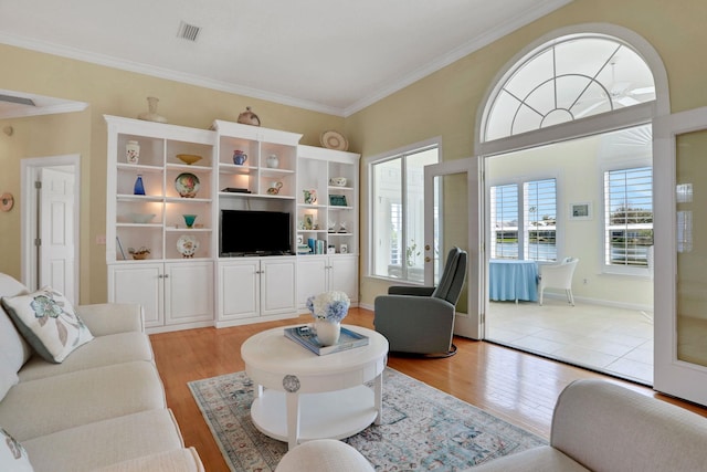 living room with ornamental molding, visible vents, and light wood-style flooring