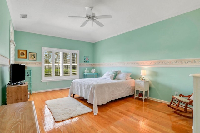 bedroom with a ceiling fan, baseboards, visible vents, and hardwood / wood-style floors