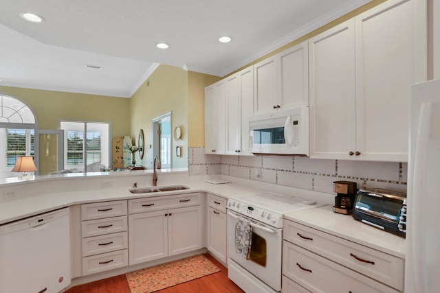 kitchen with white appliances, backsplash, a sink, and light countertops