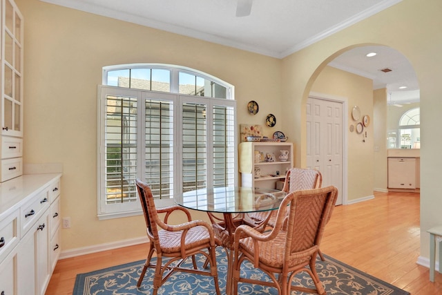 dining room with light wood-type flooring, arched walkways, and a ceiling fan