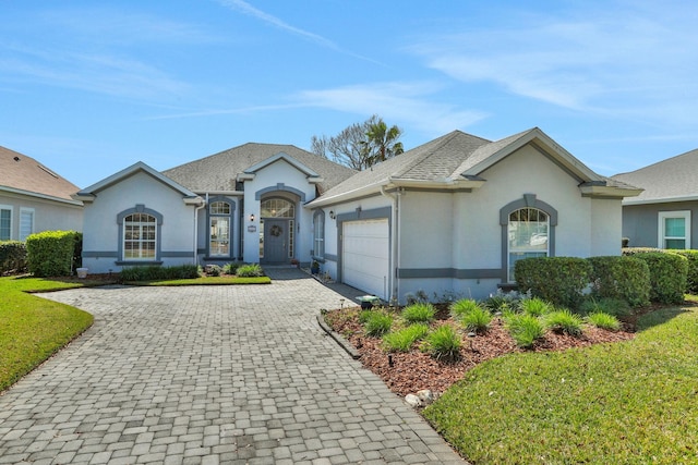 ranch-style house with a garage, decorative driveway, roof with shingles, and stucco siding