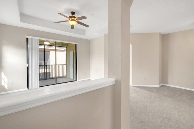 unfurnished room with ceiling fan, a raised ceiling, and carpet floors