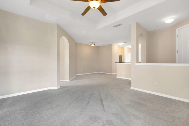 carpeted empty room featuring a raised ceiling and ceiling fan