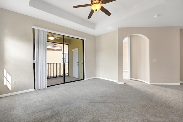 unfurnished room featuring carpet floors, a tray ceiling, and ceiling fan