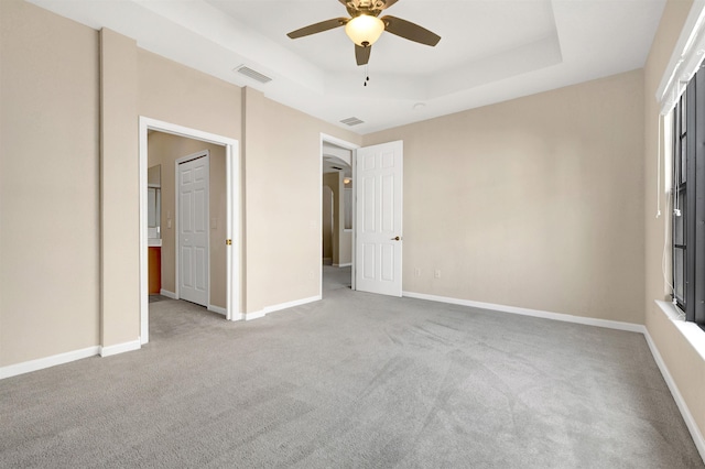 unfurnished bedroom with a tray ceiling, ceiling fan, and light colored carpet