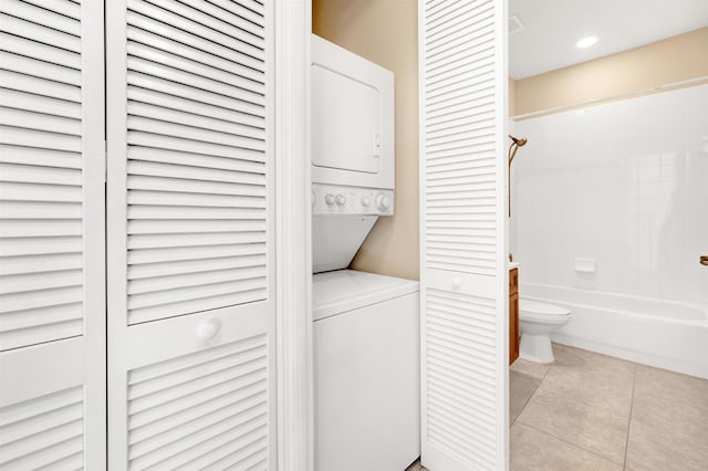 laundry area with light tile patterned floors and stacked washer / dryer