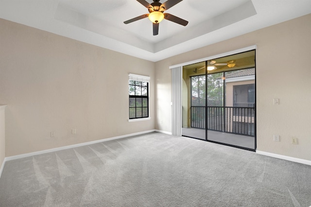 spare room featuring carpet flooring, a raised ceiling, and ceiling fan