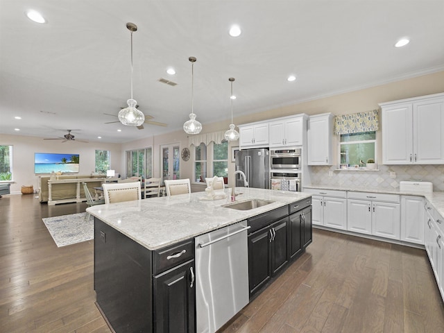 kitchen featuring white cabinets, sink, stainless steel appliances, and a center island with sink