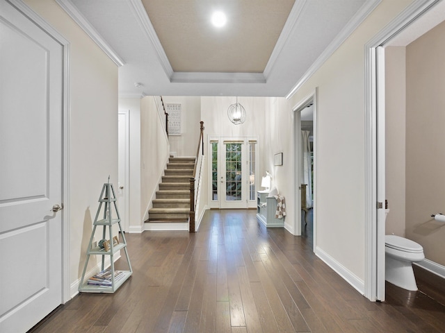 entrance foyer with a tray ceiling, crown molding, dark hardwood / wood-style floors, and an inviting chandelier