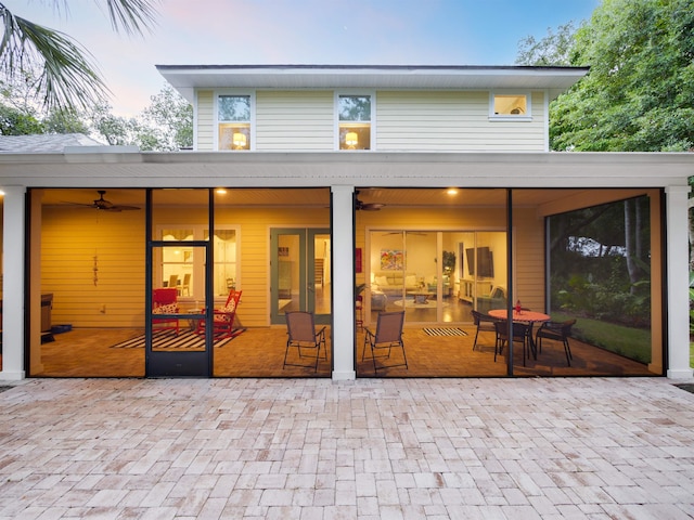 back house at dusk with ceiling fan and a patio area