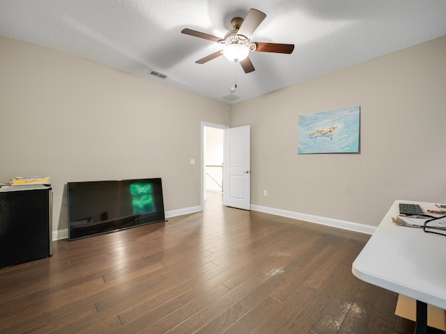 living room featuring ceiling fan, dark hardwood / wood-style flooring, and a textured ceiling