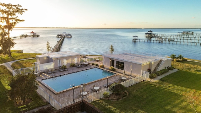 pool at dusk with a lawn and a water view