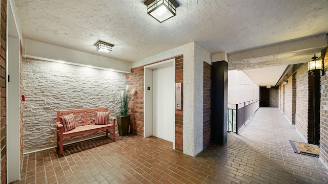 hall featuring a textured ceiling and elevator