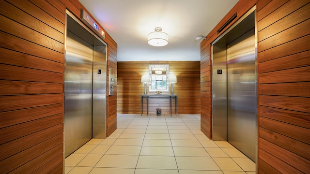 hallway featuring light tile patterned floors, elevator, a package area, and wooden walls