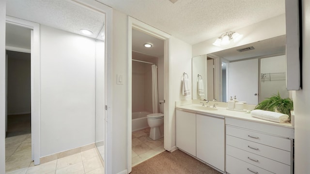 bathroom with tile patterned flooring, vanity, toilet, and a textured ceiling