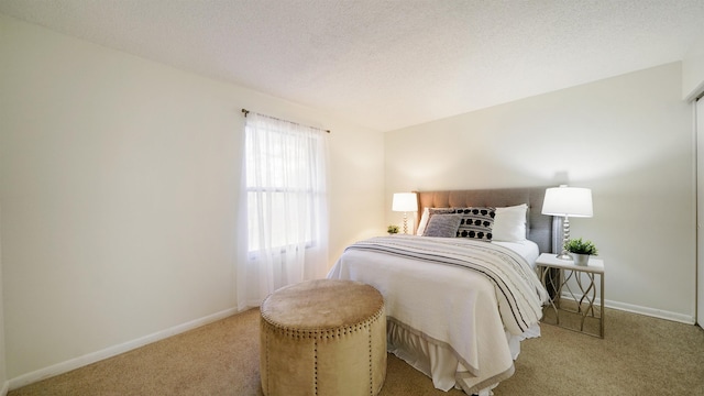 bedroom with light colored carpet and a textured ceiling