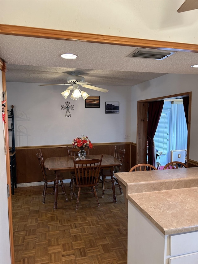 1417 Golf Ave, Ormond Beach, FL 32174 - dining area with a ceiling fan, a wainscoted wall, wooden walls, and a textured ceiling