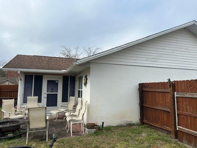 1417 Golf Ave, Ormond Beach, FL 32174 - back of house featuring roof with shingles, stucco siding, and an outdoor fire pit