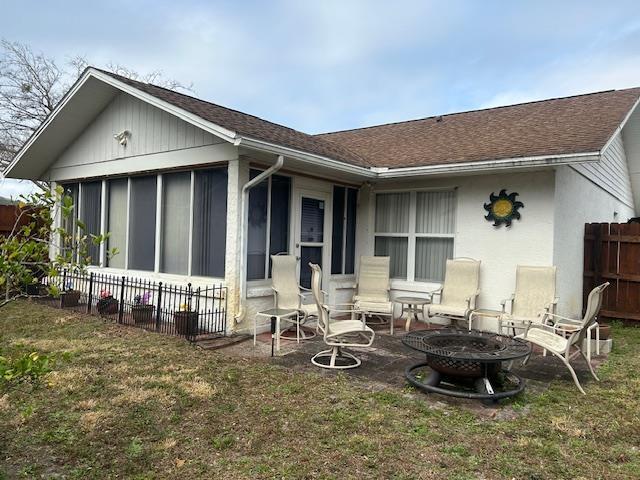 1417 Golf Ave, Ormond Beach, FL 32174 - rear view of property featuring a shingled roof, an outdoor fire pit, a sunroom, and a patio area