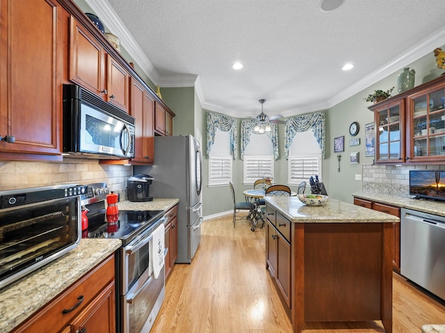 kitchen with backsplash, ornamental molding, stainless steel appliances, ceiling fan, and pendant lighting