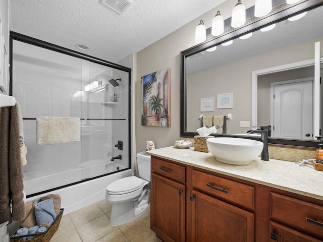 full bathroom with bath / shower combo with glass door, vanity, a textured ceiling, tile patterned flooring, and toilet