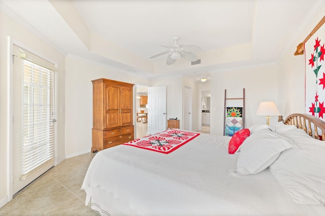 tiled bedroom featuring a tray ceiling, ceiling fan, and ensuite bathroom