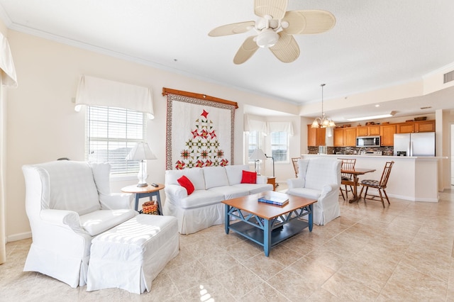 living room with ceiling fan with notable chandelier, a healthy amount of sunlight, and crown molding