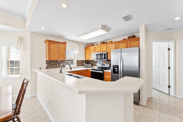 kitchen with kitchen peninsula, appliances with stainless steel finishes, backsplash, sink, and light tile patterned floors