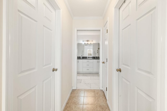 hallway with a textured ceiling, crown molding, and light tile patterned flooring