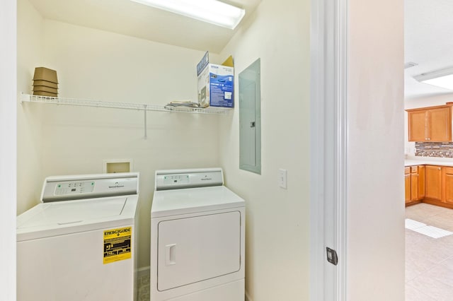 laundry area with electric panel, separate washer and dryer, and light tile patterned flooring