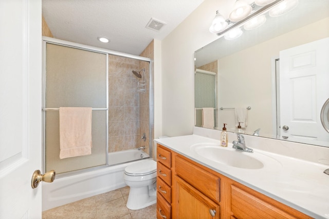 full bathroom featuring tile patterned floors, bath / shower combo with glass door, vanity, a textured ceiling, and toilet