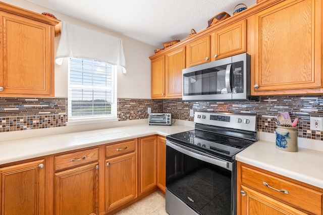 kitchen featuring backsplash, stainless steel appliances, and light tile patterned flooring