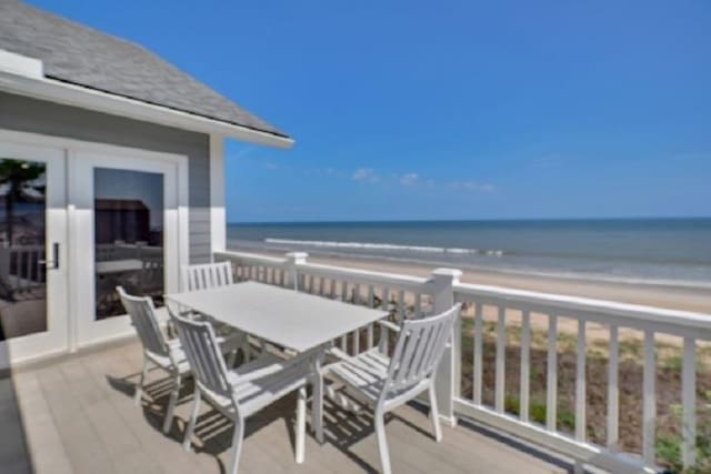 balcony featuring a view of the beach, a deck with water view, and french doors