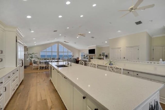 kitchen featuring a large island with sink, ceiling fan, sink, and lofted ceiling