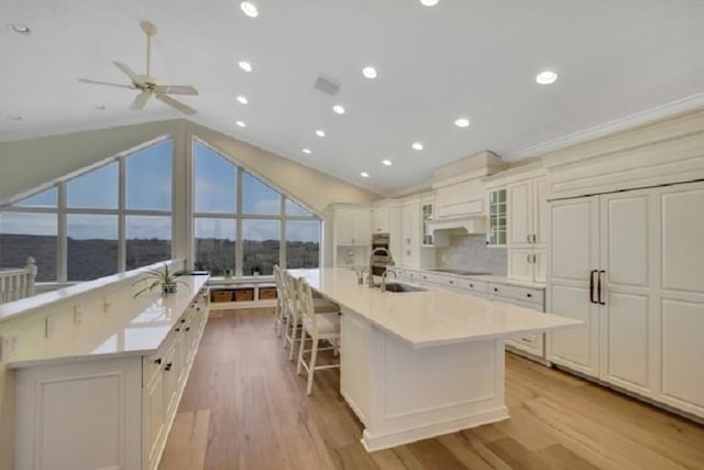 kitchen with a large island with sink, ceiling fan, sink, and light hardwood / wood-style floors